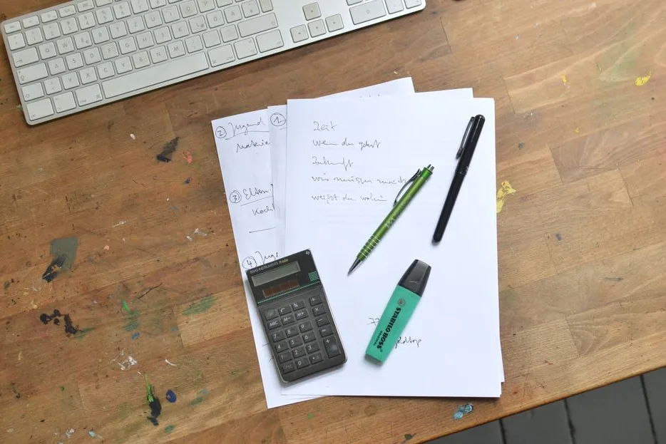 Devis papier, calculatrice et stylos sur un bureau en bois